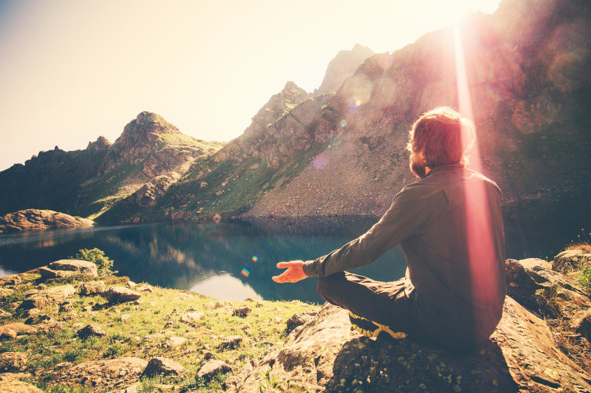 Bärtiger Mann beim entspannten Yoga an einem Bergsee.